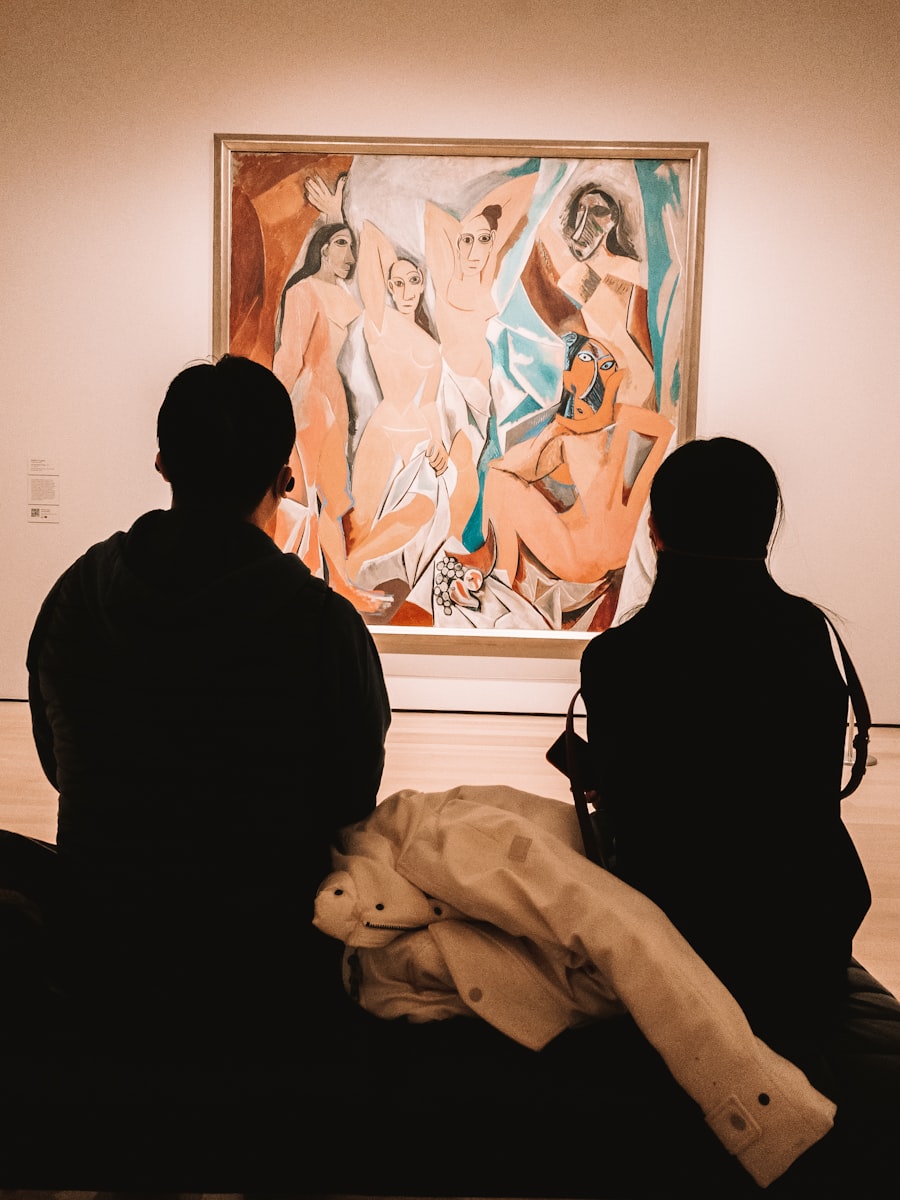 Two people seated in a museum gallery looking at a painting.