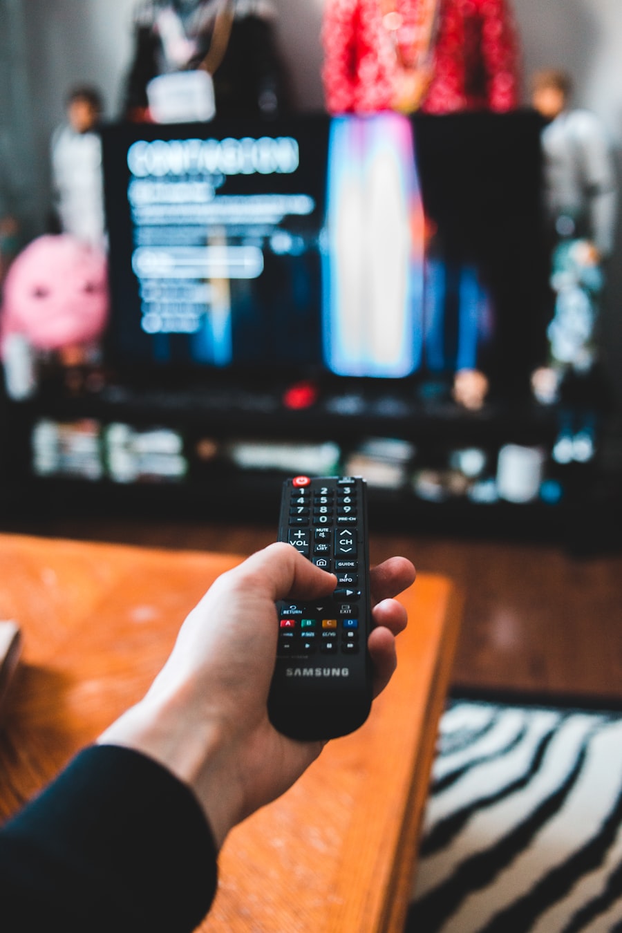 A hand holding a television remote toward a screen.